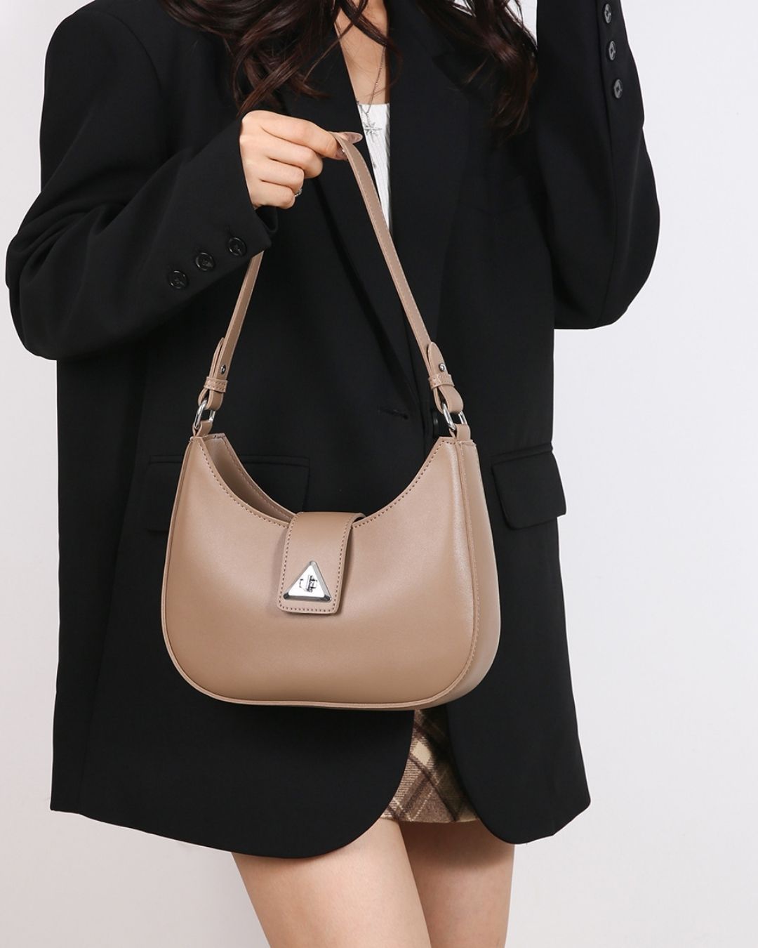 Person holding a beige handbag against a plain background